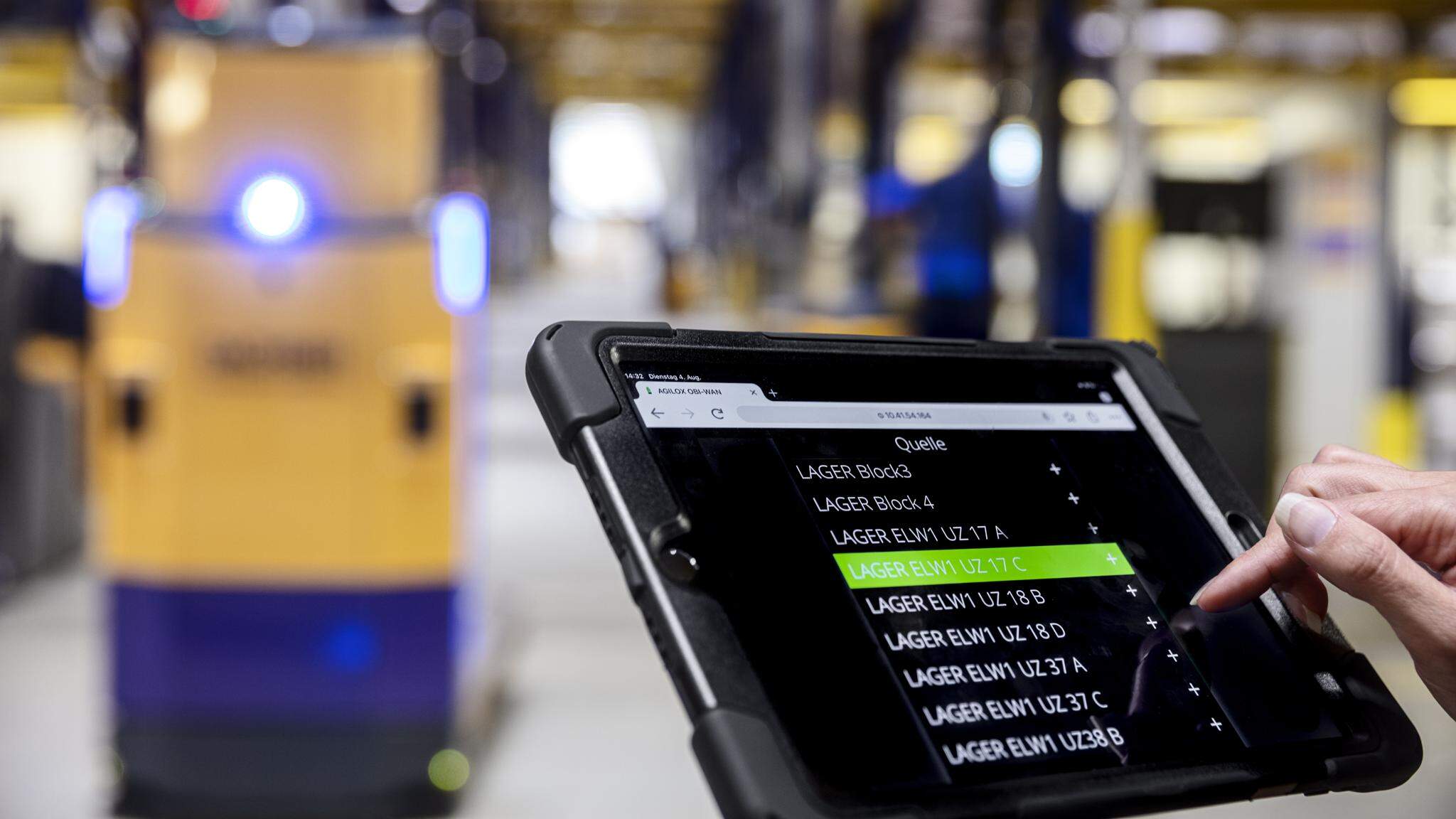 Mensch und Maschine arbeiten Hand in Hand: Ein AGV wird per Tablet im DACHSER Warehouse gesteuert.
 